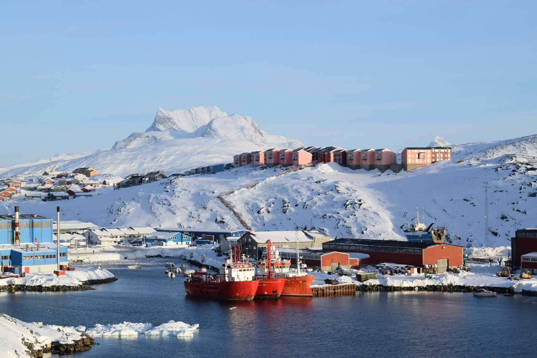 Havnen i Nuuk med skibe og bebyggelse foran snedækkede bjerge
